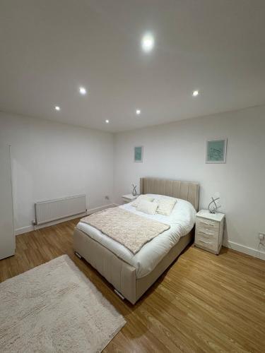 a white bedroom with a bed and a night stand at Cliffton House, Sleeps 5, Parking,Netflix, WiFi, Only 6 min to City in Killingbeck