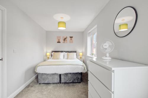 una camera da letto bianca con un letto e uno specchio di Spacious 3-Bed House with Parking and Garden ad Aylesbury