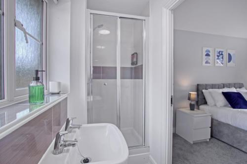 un bagno bianco con doccia e lavandino di Spacious 3-Bed House with Parking and Garden ad Aylesbury