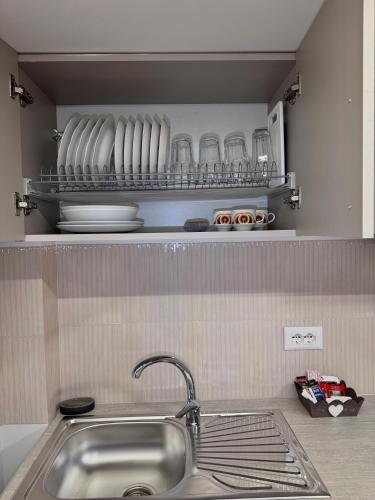 a kitchen with a sink and plates on a shelf at Nest Apartments in Tirana