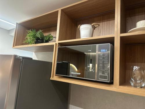 a microwave in a wooden cabinet with plants in it at Apartamentos Exclusivos no Edifício City House in Barreiras