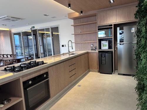 a kitchen with wooden cabinets and a stainless steel refrigerator at Apartamentos Exclusivos no Edifício City House in Barreiras