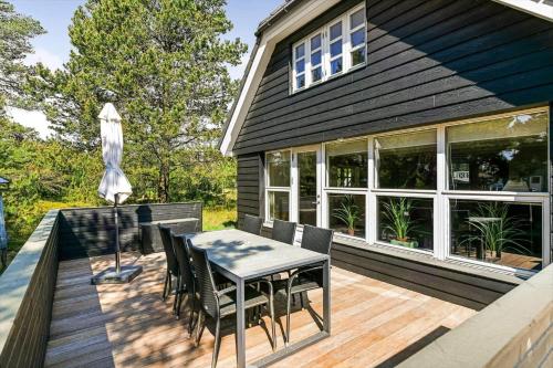 a deck with a table and chairs and an umbrella at BV395-Oksbol-Graevlingevej-1 in Oksbøl