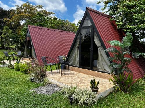 a red roofed cabin with a porch and a deck at Tilawa La Fortuna Glamping in Ángeles