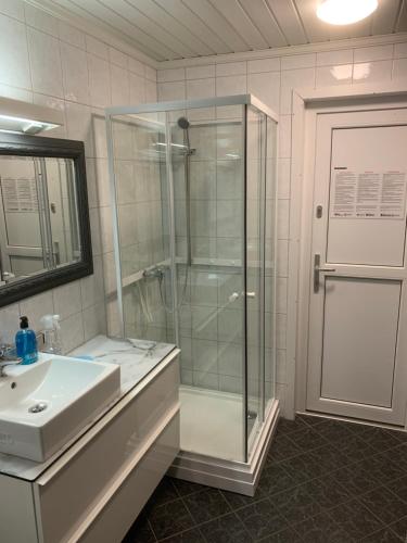 a bathroom with a glass shower and a sink at Exclusive fjordside villa with swimming pool, sauna, jacuzzi and boat hire in Sveio