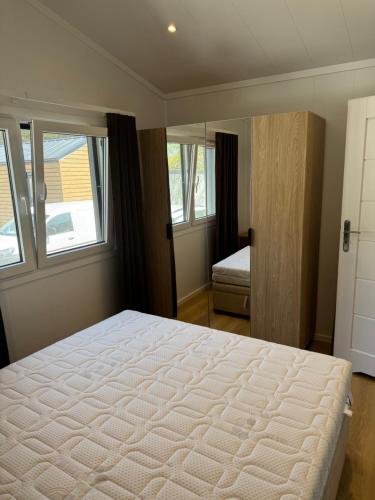 a bedroom with a large bed and two windows at Apartamenty i Domki WyDmy Międzywodzie in Międzywodzie