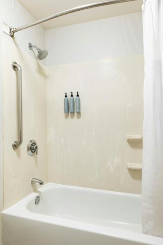a white bathroom with a tub and a shower at Courtyard St. Louis Airport/Earth City in Bridgeton