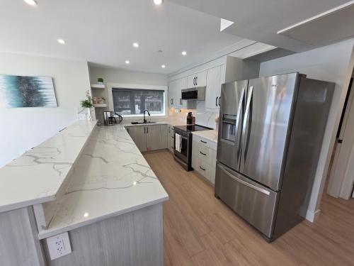 a kitchen with a stainless steel refrigerator and white cabinets at Premium Deluxe PeachView Suites 3BR in Peachland