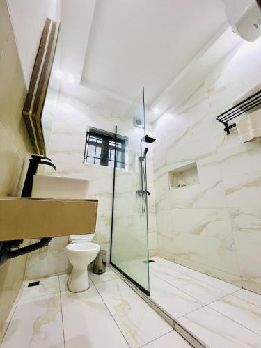 a bathroom with a toilet and a glass shower at De Fivez in Lagos