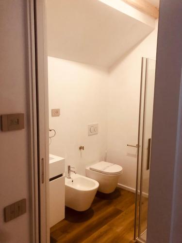 a white bathroom with a toilet and a sink at Le vecchie mura in Arco