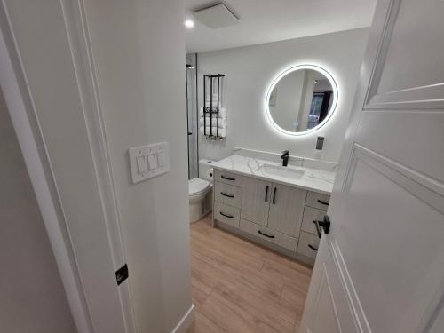 a white bathroom with a sink and a mirror at Premium Deluxe PeachView Suites 3BR in Peachland