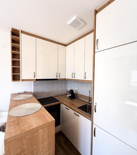 a kitchen with white cabinets and a wooden counter top at Limpio Apartman 2 in Belgrade