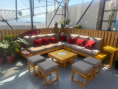 a couch with red pillows and a table and chairs at SG Paracas Hostel in Paracas