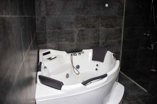 a white bath tub in a bathroom with black tiles at Noah's Ark Hotel & Suites in Maroko