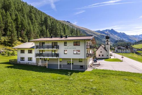 a large white building on a hill with a mountain at Haus Gstrein in Obergurgl