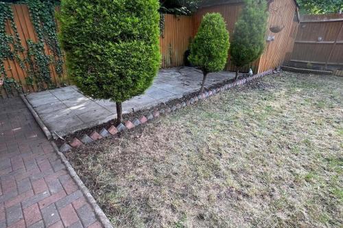 a backyard with two trees and a fence at 4-Bed Barnwell Retreat- Sleeps 9 Garden & Parking in Stevenage
