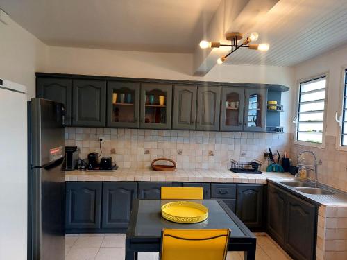 a kitchen with blue cabinets and a table with yellow chairs at TI-KAZ fleurie, l'escapade bouillonaise in LʼAjoupa-Bouillon
