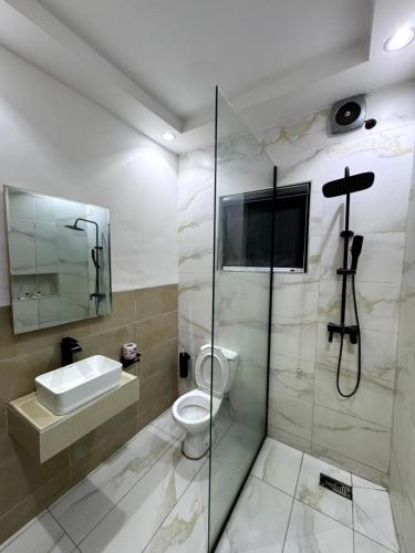 a bathroom with a shower and a toilet and a sink at De Fivez in Lagos