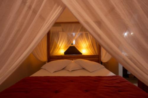 a bedroom with a canopy bed with white curtains at La Villa By Ferdi'Nan in Grand-Bourg