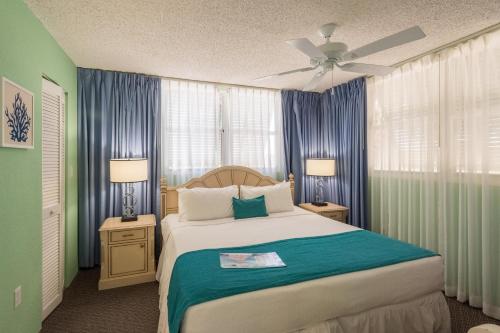 キーウェストにあるSunrise Suites Cozumel Suite #112のベッドルーム1室(青いカーテン付きの大型ベッド1台付)