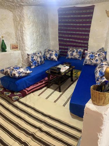 a living room with a blue couch and a table at كهوف يحيى للسياحة والمبيت البهاليل in Bhalil