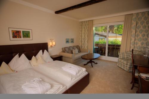 a hotel room with a bed and a chair and a window at Romantik SPA Hotel Seefischer in Döbriach