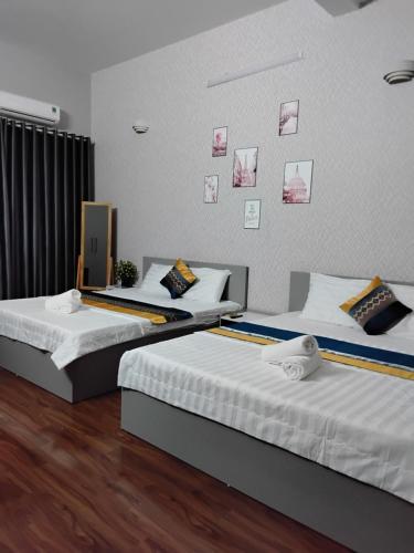 two beds in a hotel room with pictures on the wall at Hotel LOAN ĐÀI in Bùi Tiếng