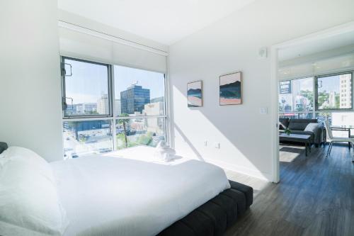 a bedroom with a white bed and large windows at Multiple Hollywood Apartments Hub in Los Angeles