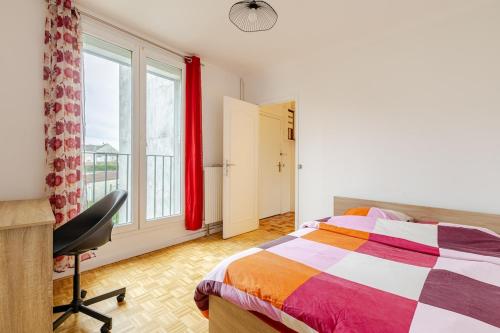 a bedroom with a bed and a desk and a window at appartement proche paris et Roissy in Persan