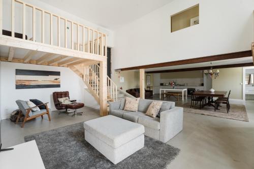 a living room with a staircase and a couch and chairs at MONTD'OR Azenha - by RowdHouses in Paços de Gaiolo