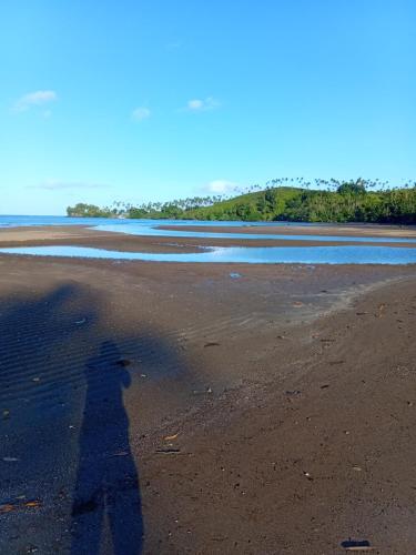 a shadow of a person walking on a beach at Emma's Homestay Explorer in Taveuni