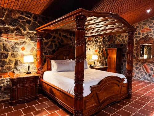 a bedroom with a wooden canopy bed and two lamps at Le Suisse Spa in Santa Lucía Milpas Altas
