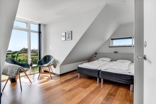 a bedroom with a bed and chairs and a window at BV284-Blavand-Blavand-Strand-4 in Blåvand