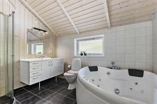 a white bathroom with a tub and a toilet at BV129-Blavand-Sonderballevej-47 in Blåvand