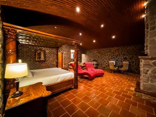 a bedroom with a bed and chairs in a room at Le Suisse Spa in Santa Lucía Milpas Altas