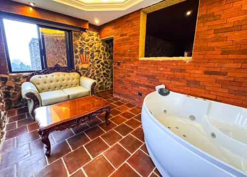 a bathroom with a tub and a couch and a table at Le Suisse Spa in Santa Lucía Milpas Altas