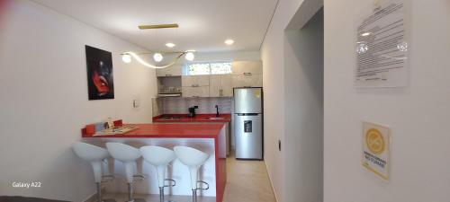 a kitchen with a red counter and white stools at Hotel y Cabañas Parinzzi in Guatapé