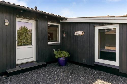 a black house with a white door and a potted plant at BV302-Blavand-Gronnevej-12 in Blåvand