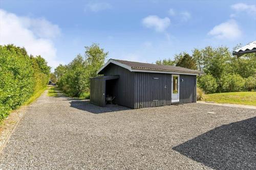 a black garage with a white door in a driveway at BV302-Blavand-Gronnevej-12 in Blåvand