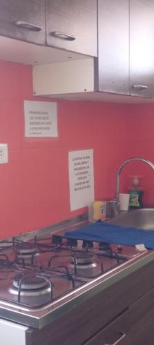 a stove top in a kitchen with a red wall at Apartamento central Yahweh in San Andrés