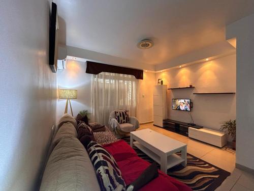 a living room with a couch and a flat screen tv at UMO Urban Suites in Ciudad de Malabo