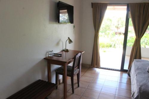 a room with a desk with a lamp and a bed at Hotel Colinas del Sol in Atenas