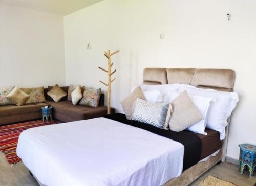 a bedroom with a white bed and a couch at Villa Bouzama in Essaouira