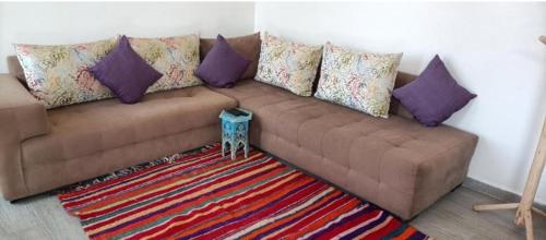 a brown couch with purple pillows and a rug at Villa Bouzama in Essaouira