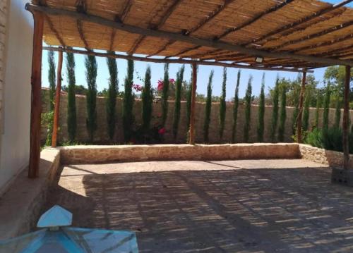 a patio with a wooden pergola and a fence at Villa Bouzama in Essaouira