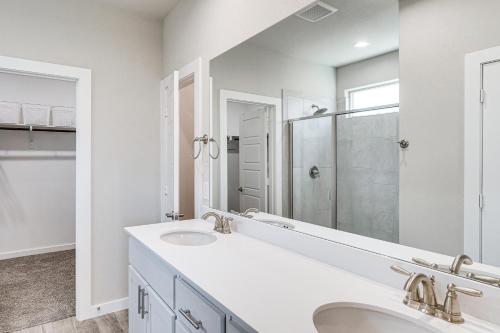 a bathroom with two sinks and a large mirror at Spacious Family Home with Office in Midland-Odessa! in Midland