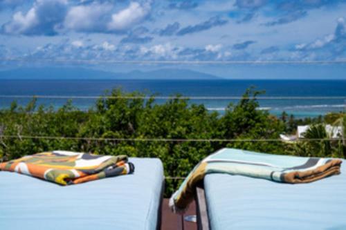 two beds on a balcony with a view of the ocean at La Villa By Ferdi'Nan in Grand-Bourg