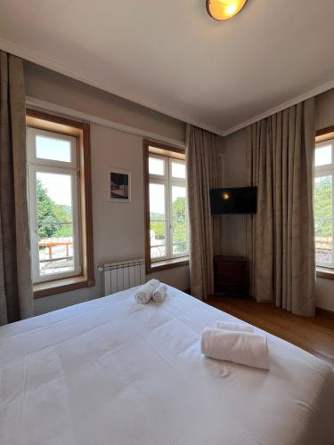 a bedroom with a large white bed with windows at Casas do Souto in Lousada
