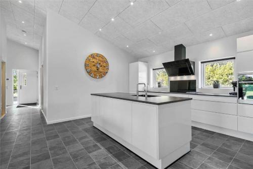 a kitchen with white cabinets and a clock on the wall at BV144-Blavand-Horntoftvej-13 in Blåvand
