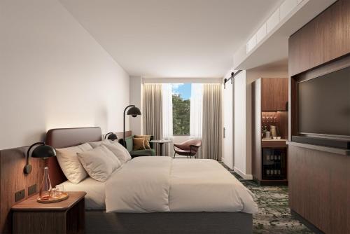 a hotel room with a bed and a flat screen tv at Crowne Plaza Melbourne Carlton by IHG in Melbourne